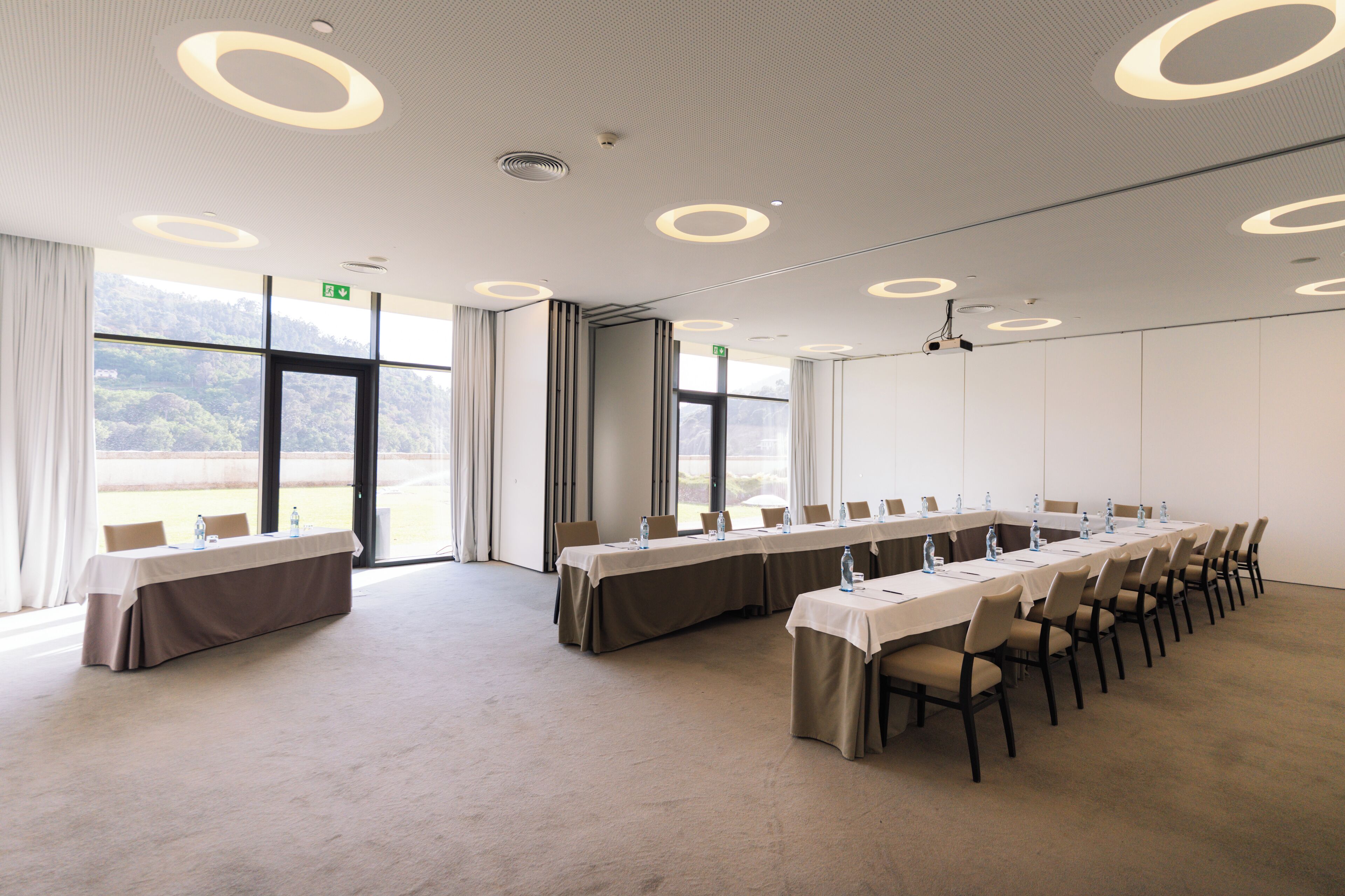 A conference room with a long table, chairs, and a projector screen.