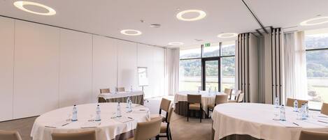 A conference room with round tables, chairs, and water bottles.