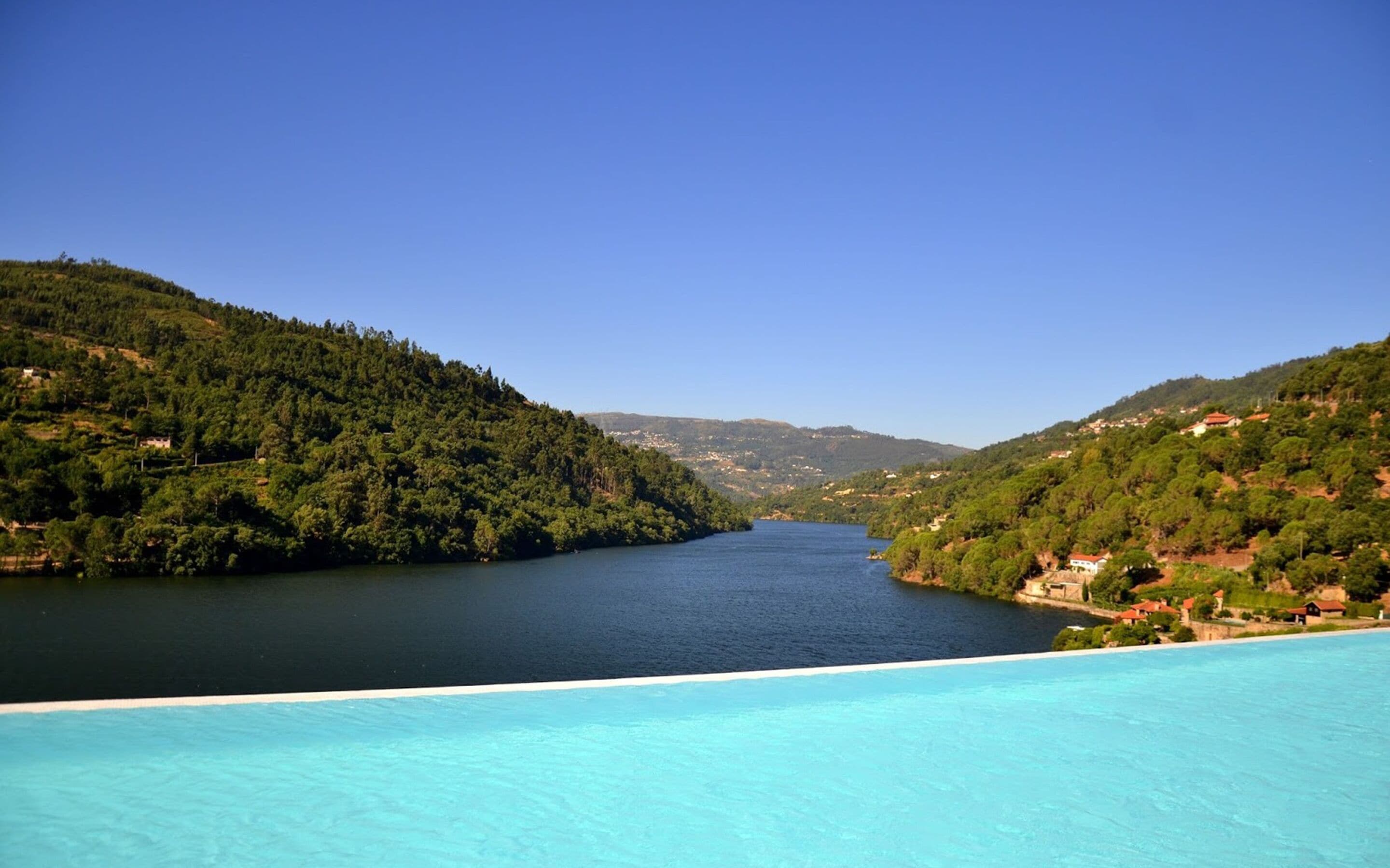 Vista de un lago rodeado de colinas bajo un cielo despejado.
