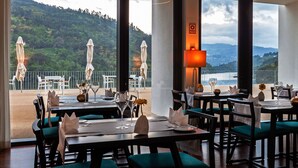 A restaurant with tables set for dining, outdoor umbrellas, and a view of a mountainous landscape. - Douro Royal Valley Hotel & SPA (Baiao)