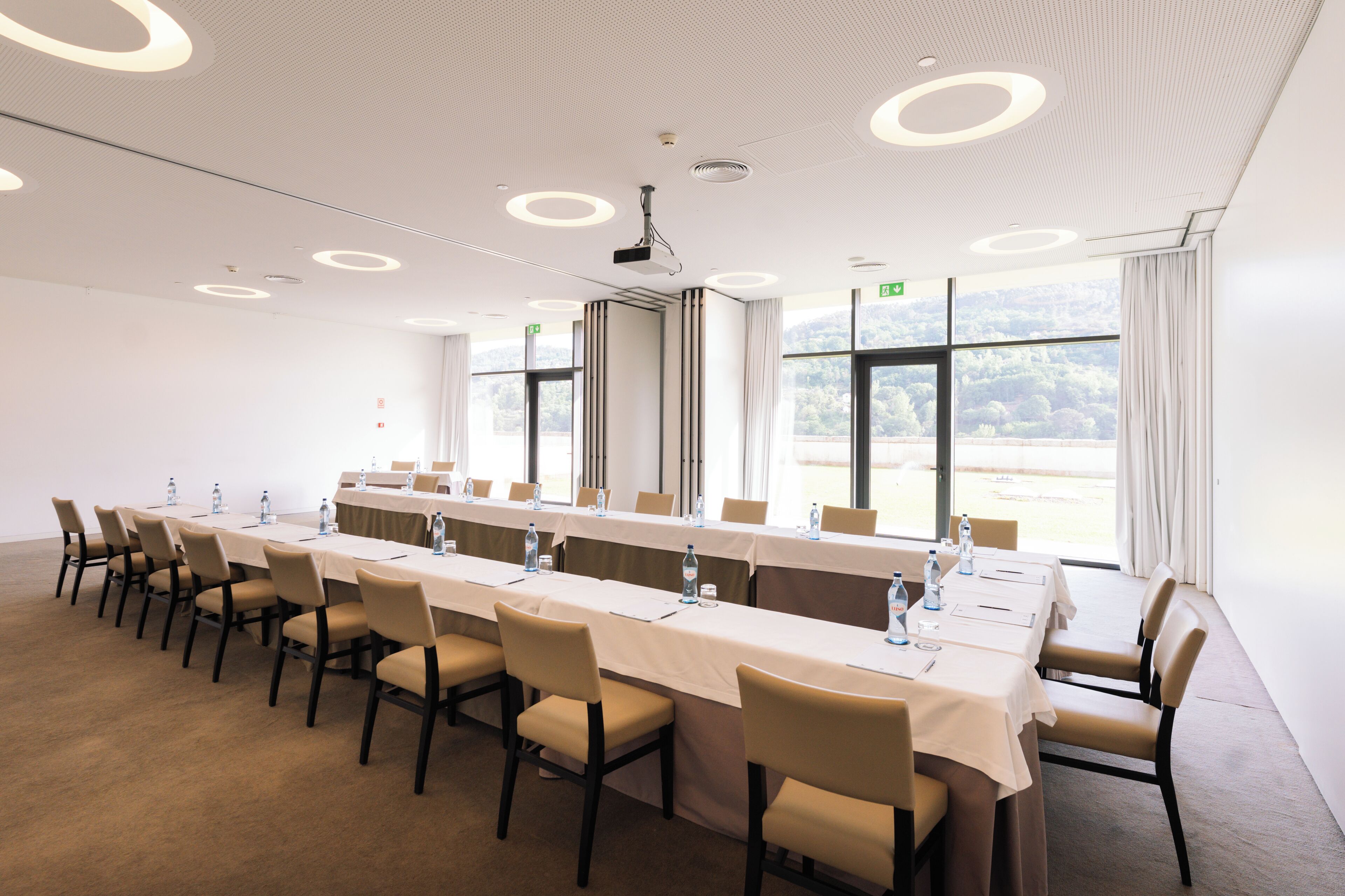 A conference room with a long table, chairs, water bottles, and a projector.
