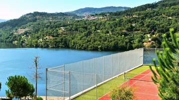Una cancha deportiva cercada con vista a un lago y colinas.