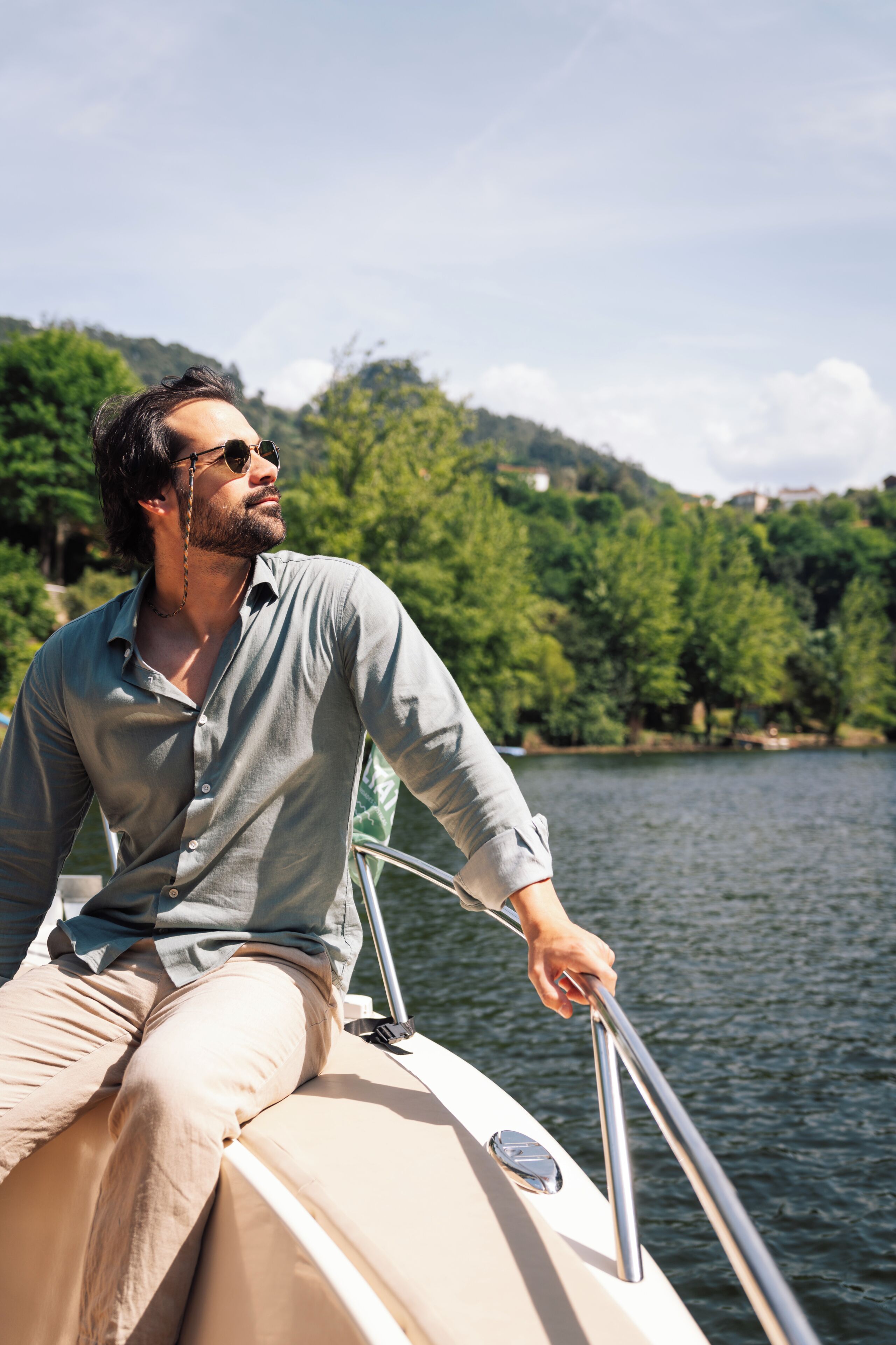 A person on a boat with a view of a lake and trees in the background.