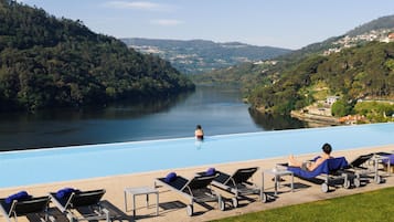 Una piscina con sillones de descanso y vistas a un lago rodeado de colinas.