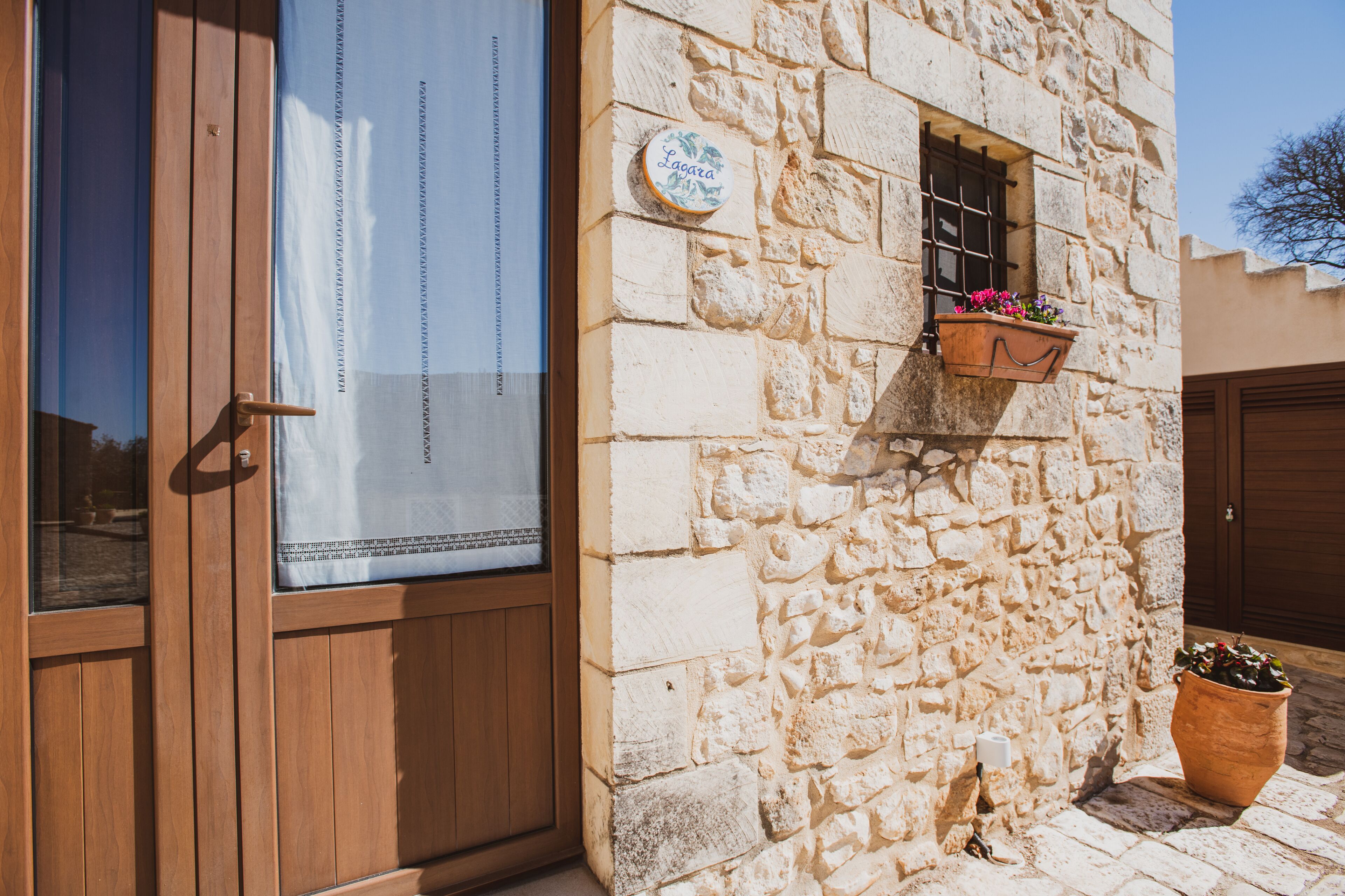 Un edificio in pietra con una porta in legno, una finestra vista inclusa e un fioriere con fiori.