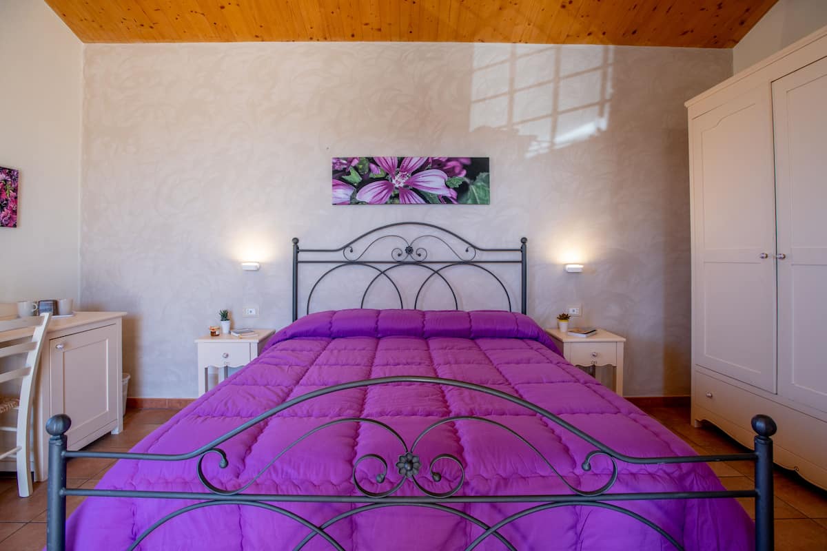 A bedroom with a bed, a desk, and a wardrobe.