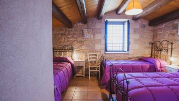 Une chambre avec deux lits, une chaise, une petite table et une fenêtre.