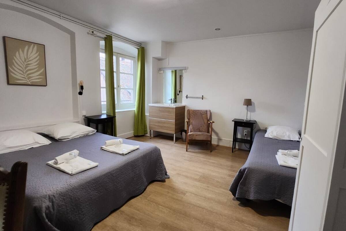 A hotel room with two beds, a desk, a chair, a mirror, and a window with curtains.