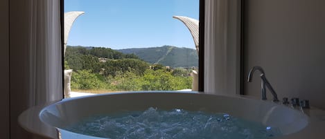 Uma banheira com vista para uma paisagem montanhosa através de uma janela.