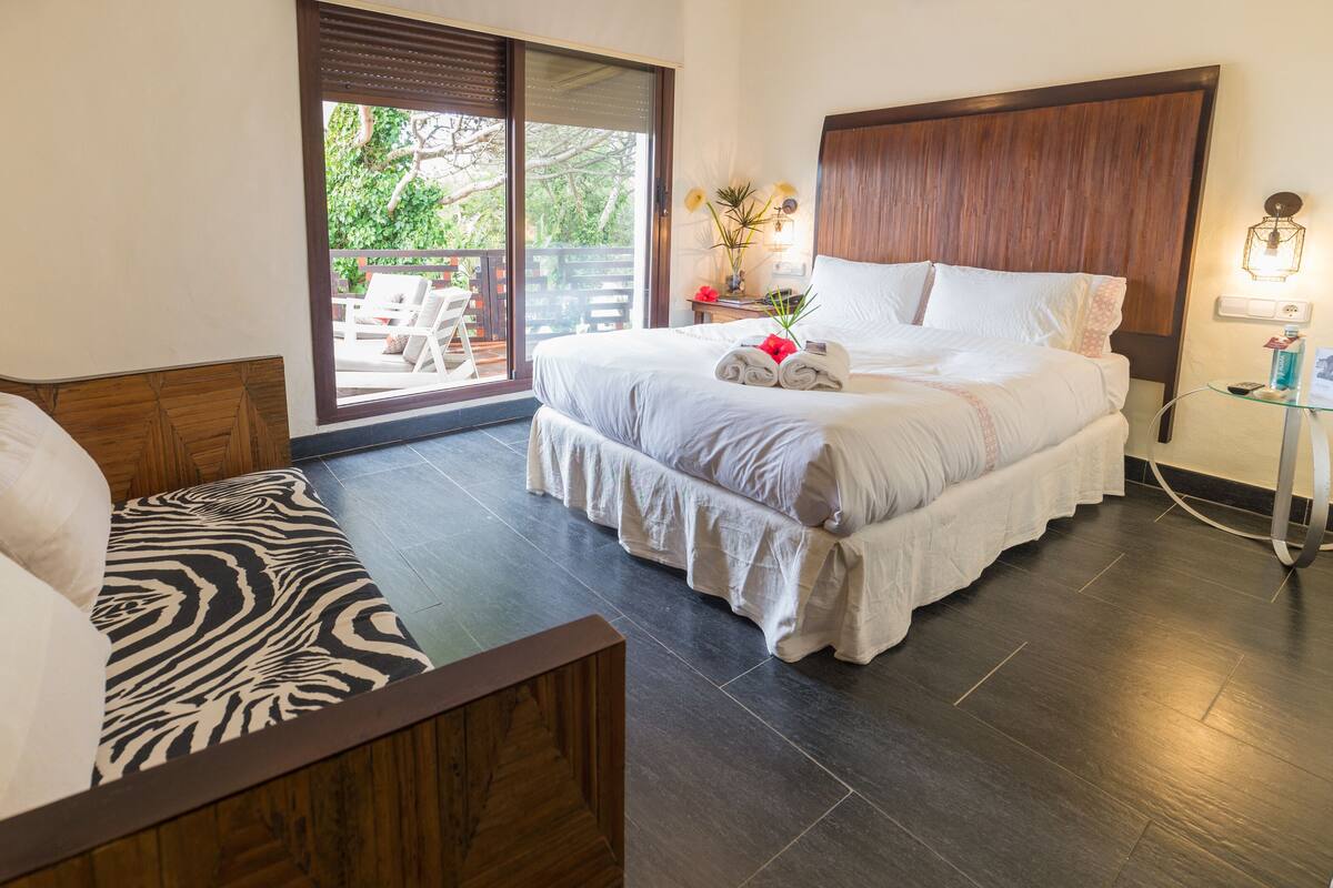 A hotel room with a bed, a sofa, and a view of the outdoors.