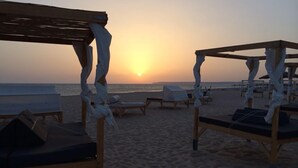 A beach with wooden sun loungers and a wooden pergola structure. - Hotel El Varadero (Tarifa)