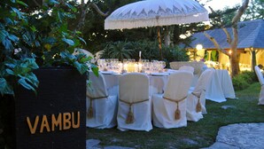 An outdoor dining area with round tables, white tablecloths, and chairs with tassels. A sign with the word "VAMBU" is visible. - Hotel El Varadero (Tarifa)