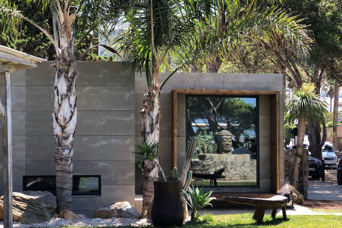 A modern outdoor area with a stone wall, a wooden bench, and a cactus plant.
