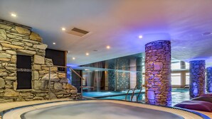 Un área de spa con un jacuzzi, pilares de piedra y una pared de piedra.