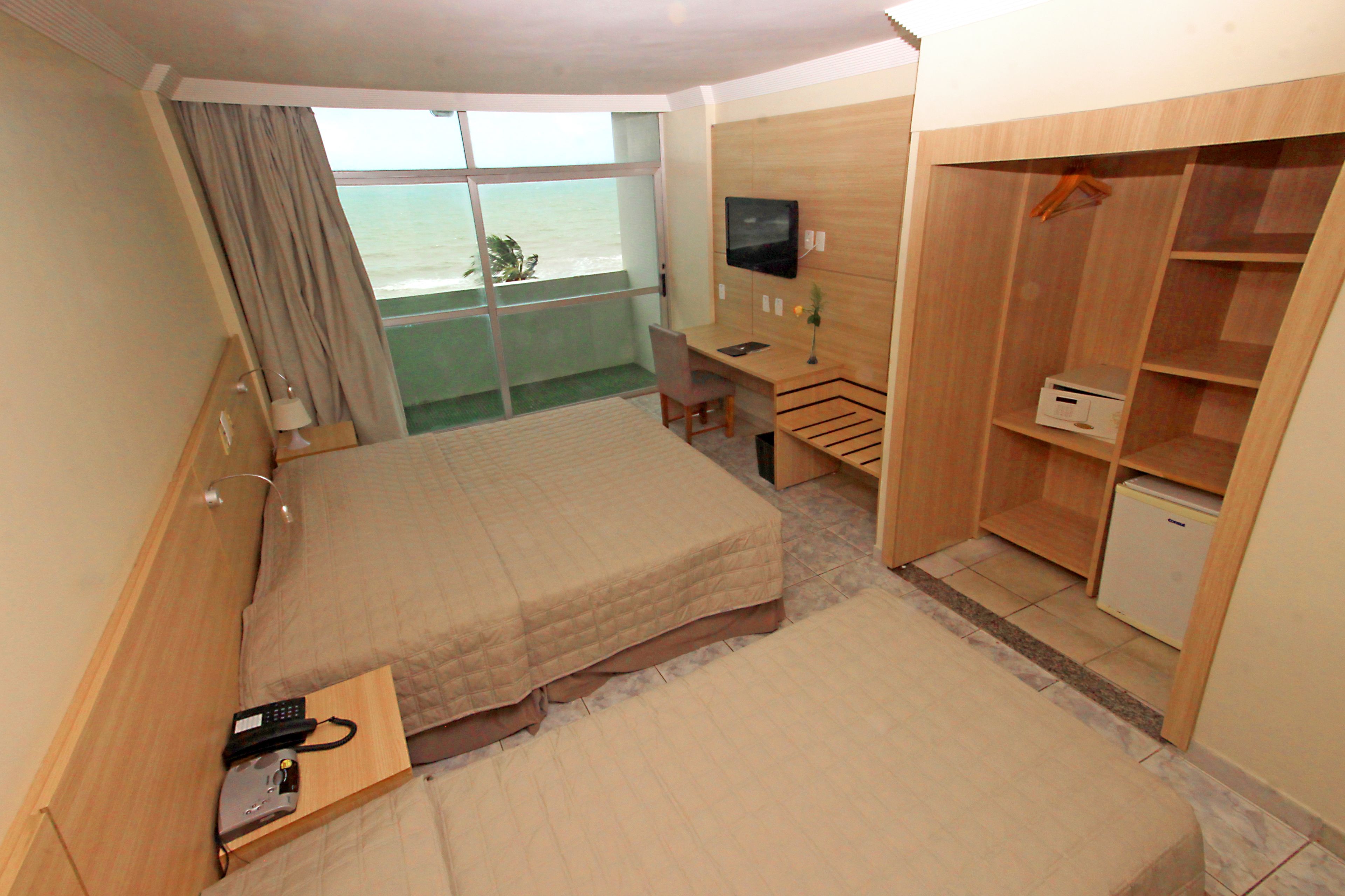 A hotel room with a bed, a desk, a TV, and a wardrobe.