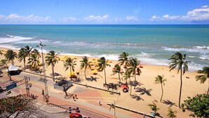 A beach with palm trees, a road, and a view of the ocean. - Jangadeiro Hotel e Convenções (Recife)