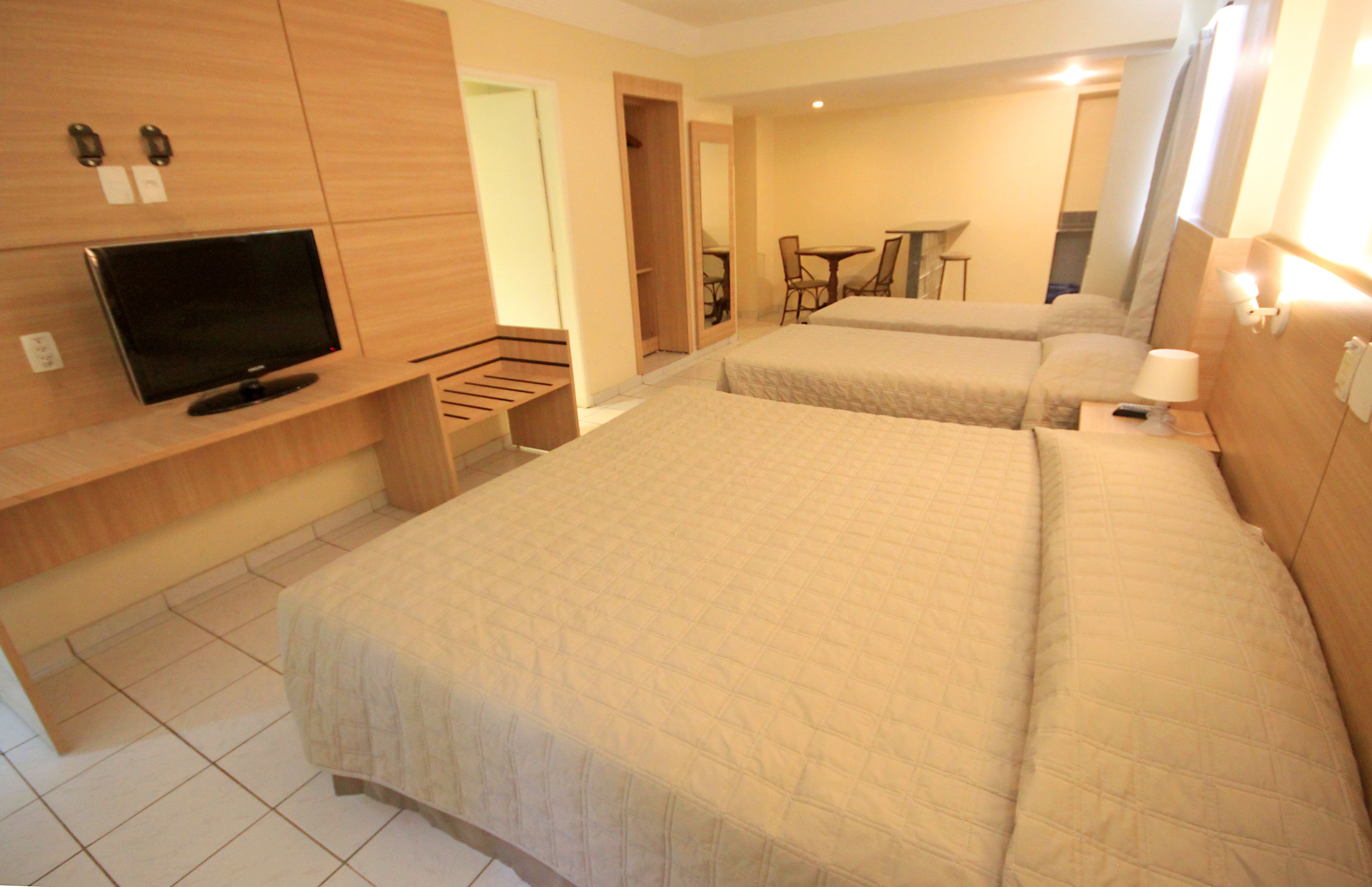 A hotel room with two beds, a TV, a desk, and a chair.