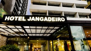The entrance to Hotel Jangadeiro with a modern design, featuring a prominent sign, a staircase leading to the entrance, and a glass facade. - Jangadeiro Hotel e Convenções (Recife)