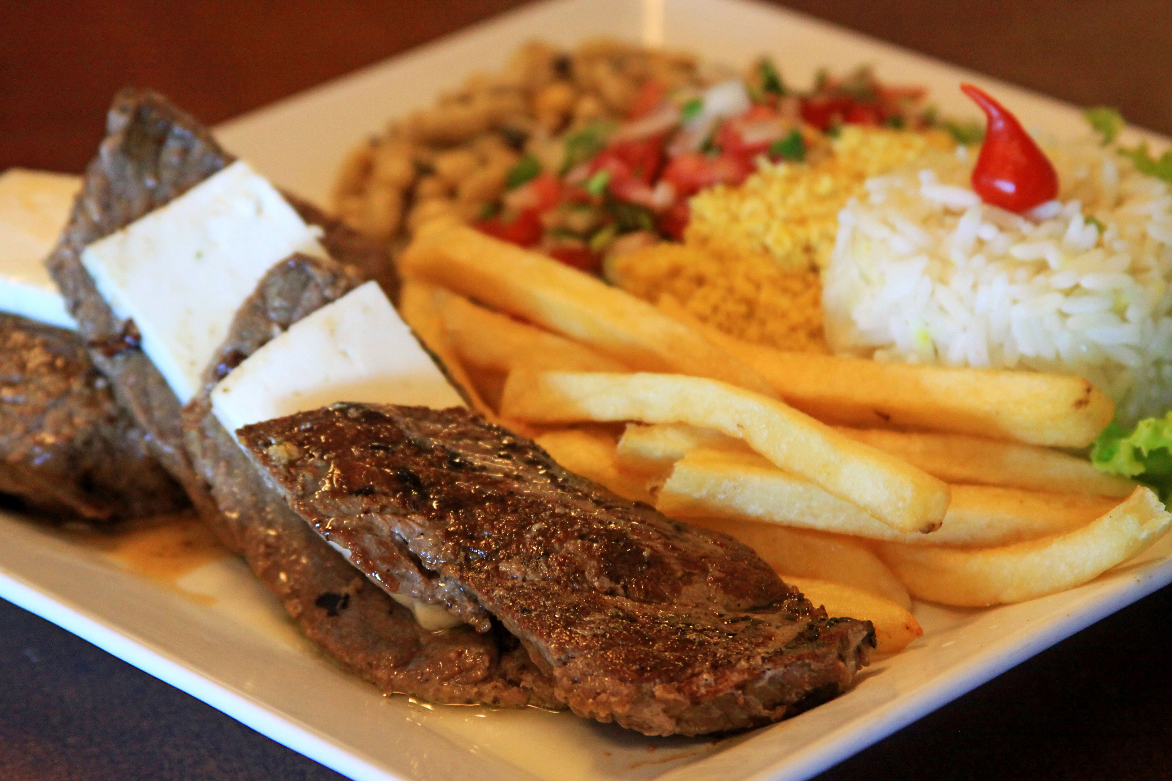 A plate with steak, fries, rice, and a salad.