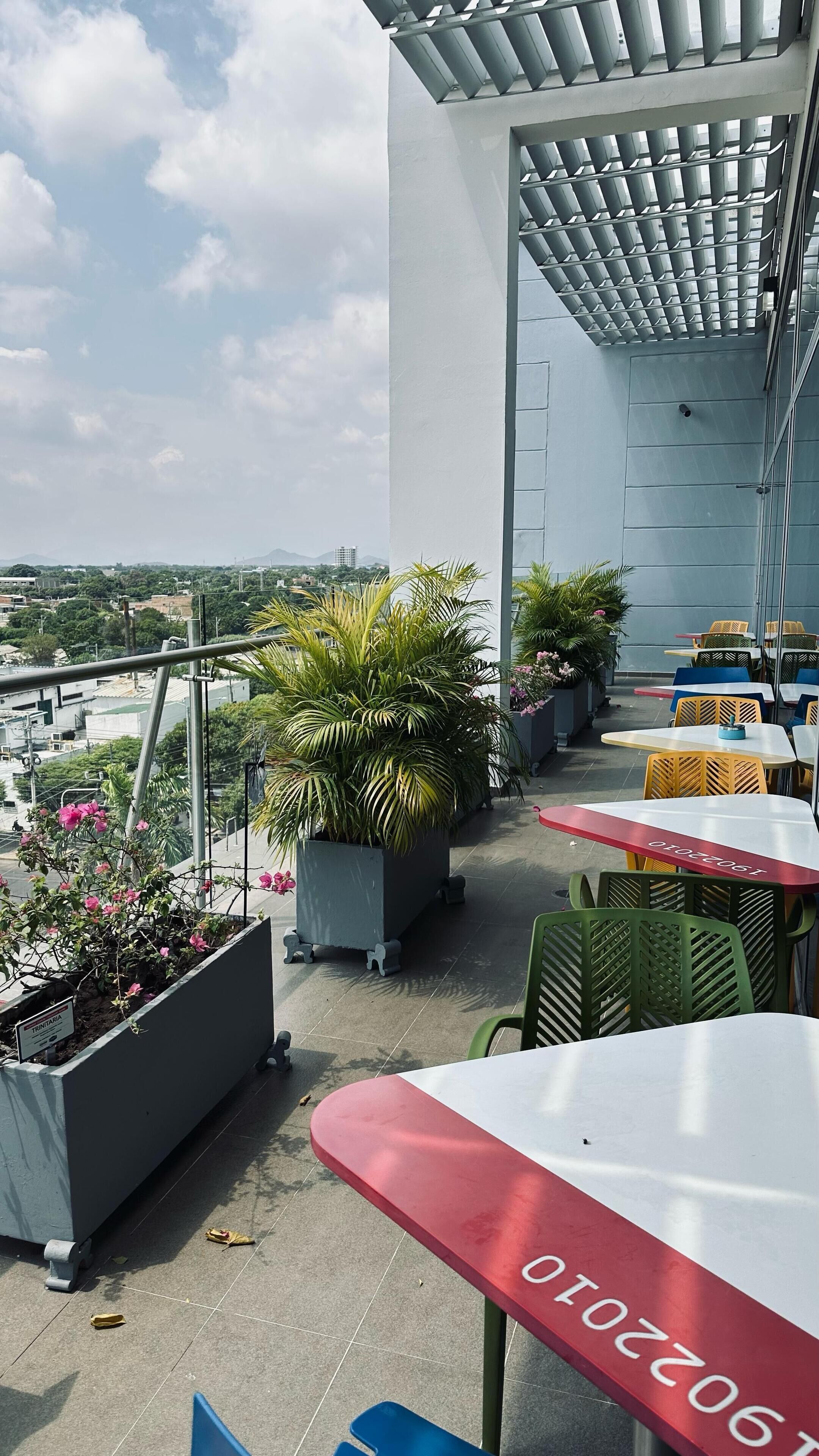 A rooftop terrace with outdoor seating, potted plants, and a view of the cityscape.
