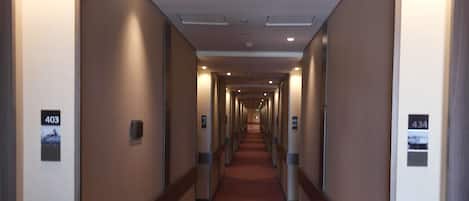 Een hotelgang met een rood tapijt, genummerde deuren en een modern design.