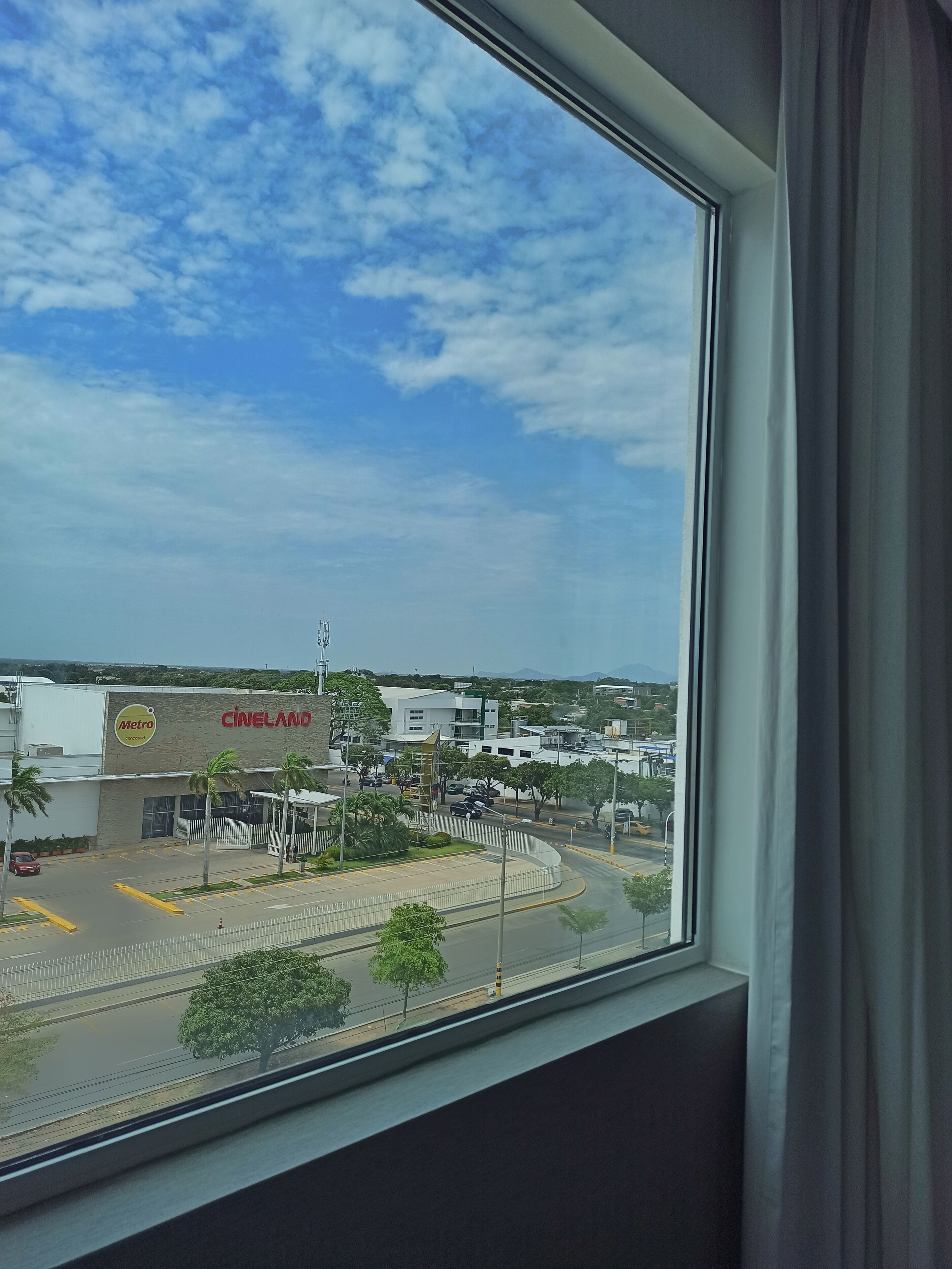 Vista desde una ventana sobre un estacionamiento y un edificio con un letrero que dice "CINELAND".