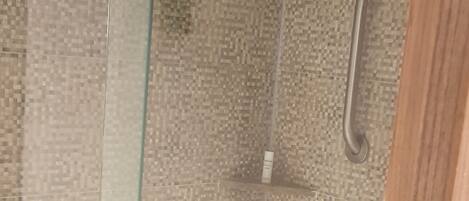 A glass-enclosed shower area with a textured wall and a wooden door.