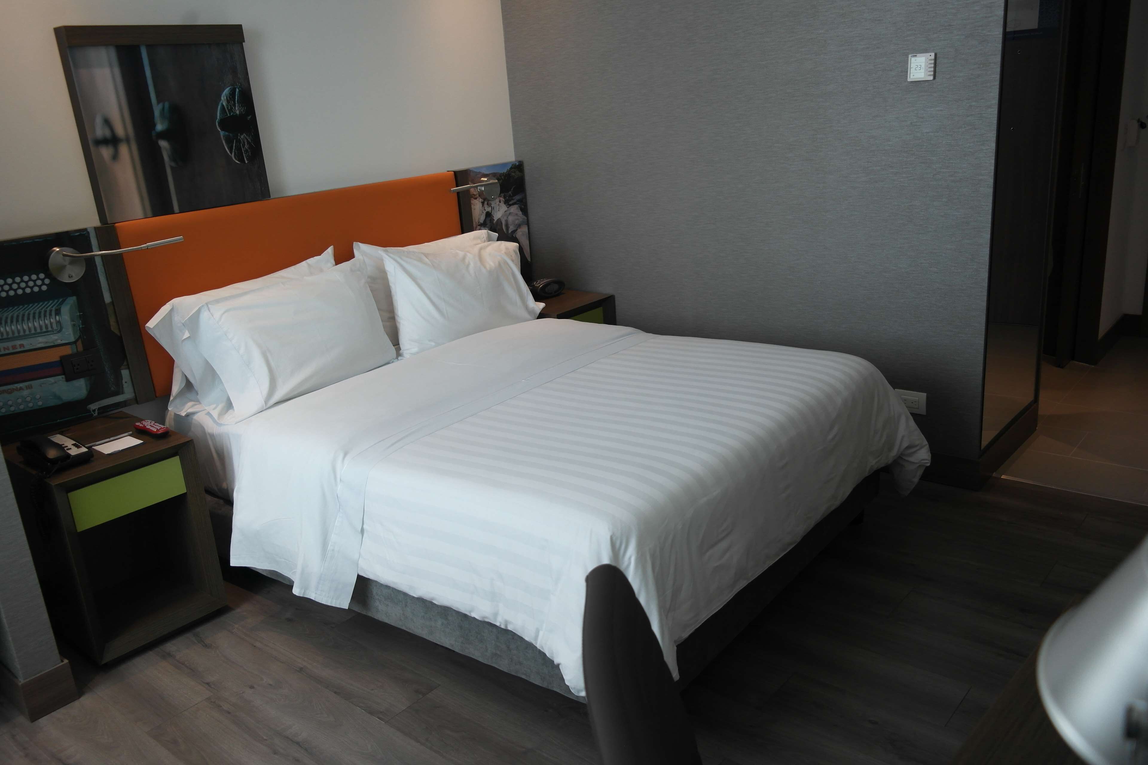 Ein Hotelzimmer mit Bett, Nachttisch, Schreibtisch mit Computer und Spiegel.