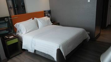 Ein Hotelzimmer mit Bett, Nachttisch, Schreibtisch mit Computer und Spiegel.
