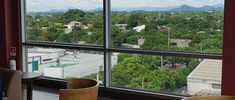 A hotel room with large windows, a red carpet, wooden chairs, and a small table.