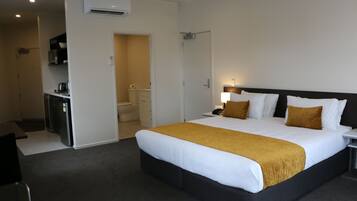 Habitación de hotel con una cama grande, un escritorio, una silla, un microondas y una kitchenette pequeña.