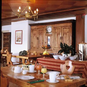 Enjoy a formal dining experience in this elegantly set room with a wooden table, chandelier, and traditional cabinetry.