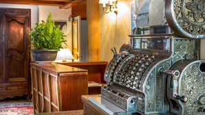 A vintage typewriter, wooden furniture, and a potted plant in a room with stone walls and a wooden ceiling. - Les Crêtes Blanches (Val-d'Isere)