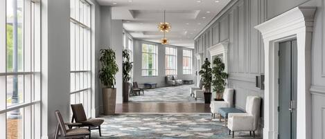 A spacious lobby with large windows, a patterned carpet, and modern furniture.