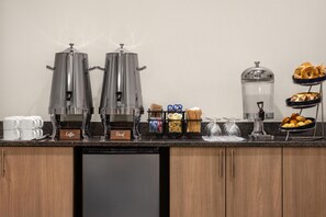 Un buffet de petit-déjeuner proposant du café ordinaire et du café décaféiné, une variété de viennoiseries et un distributeur d’eau.