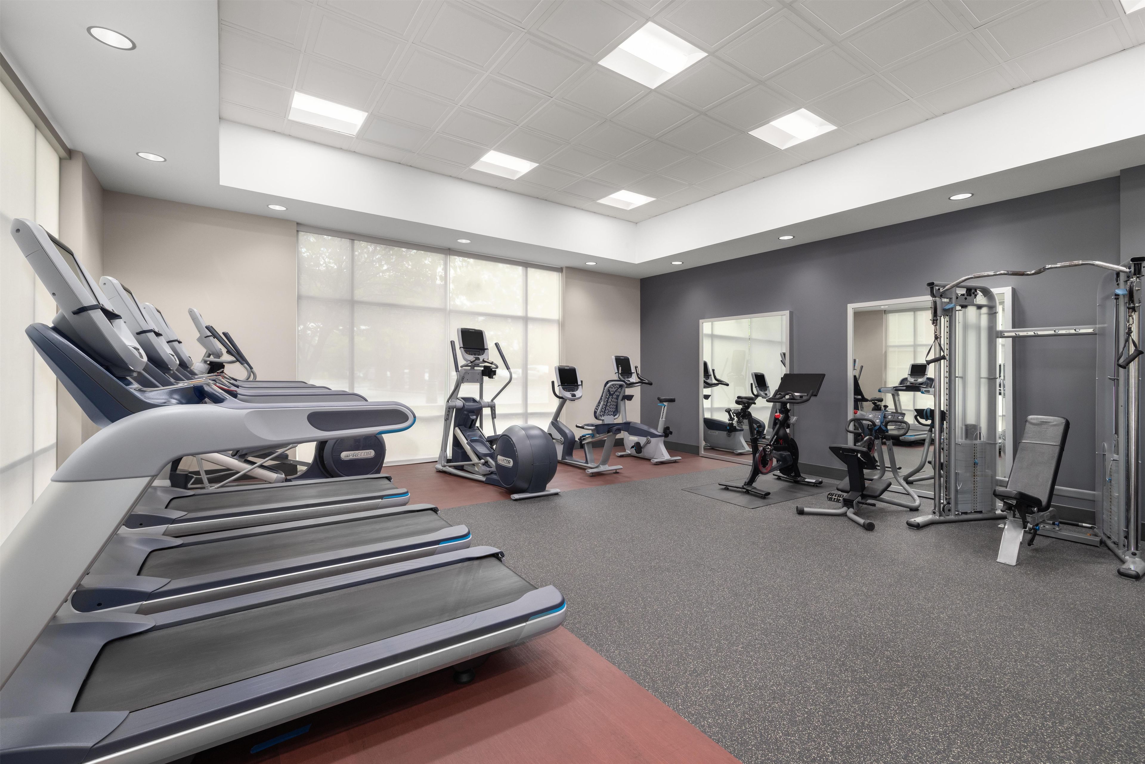 Une salle de sport équipée de tapis de course, de vélos elliptiques et de matériel de musculation.
