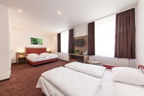 A hotel room with two beds, a desk, a chair, a TV, and a window with curtains. - Hotel Excelsior (Dortmund)