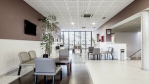 A spacious lobby with a reception desk, seating area, and large windows allowing natural light. - Residencia Universitaria Resa Giner de los Ríos - Hostel (Alcala de Henares)
