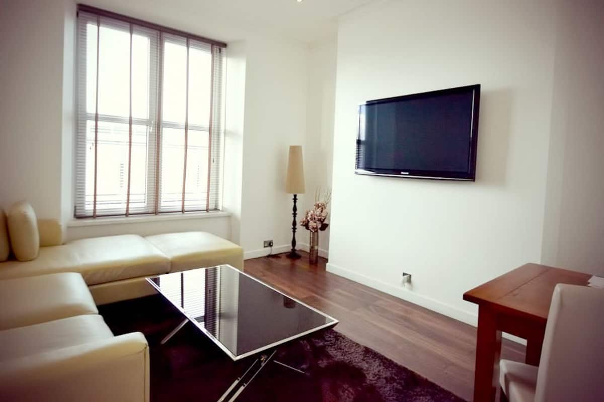 Departamento de lujo, 1 habitación, vista a la ciudad | Área de sala de estar | Televisión de pantalla plana
