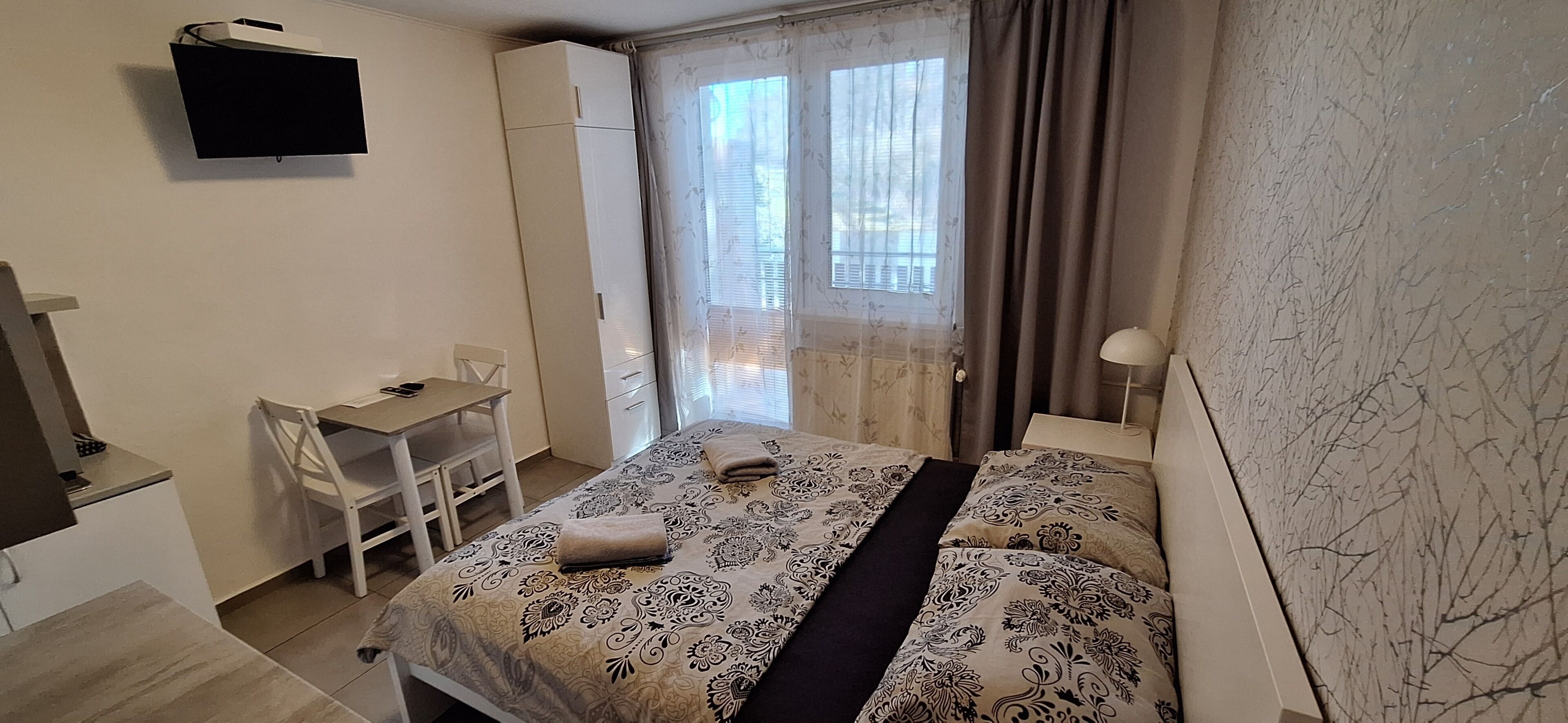 Une chambre à coucher comprenant un lit, un bureau, une chaise, une armoire et un téléviseur.