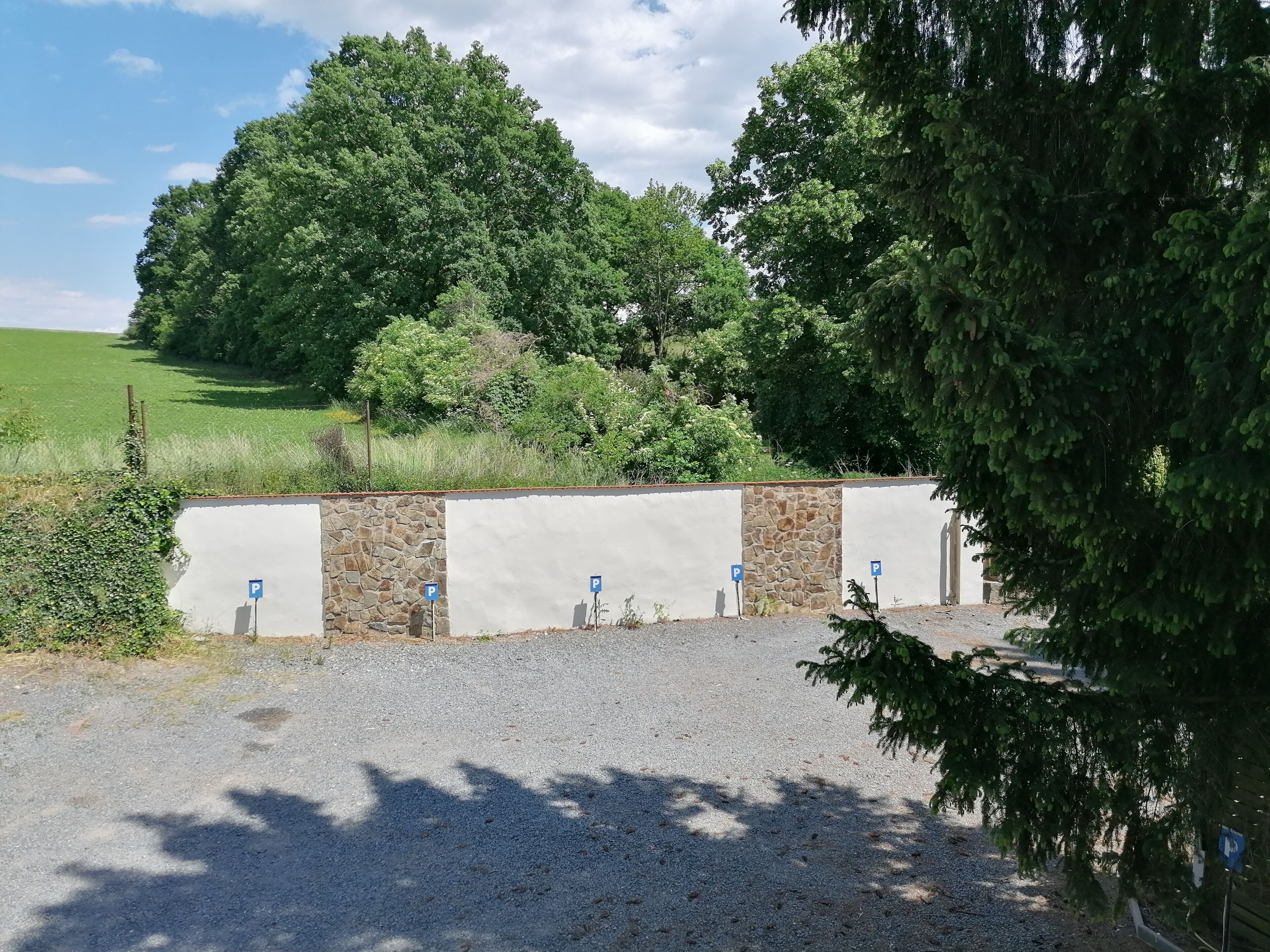 A parking area with stone walls and blue parking signs.