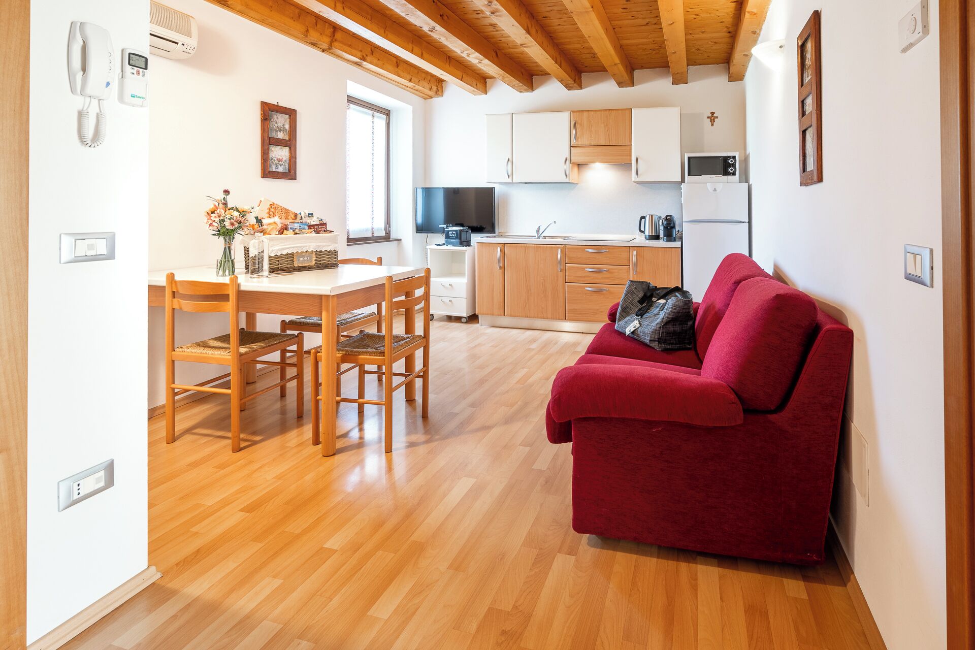 A compact living space with a dining area, kitchenette, and a red sofa.