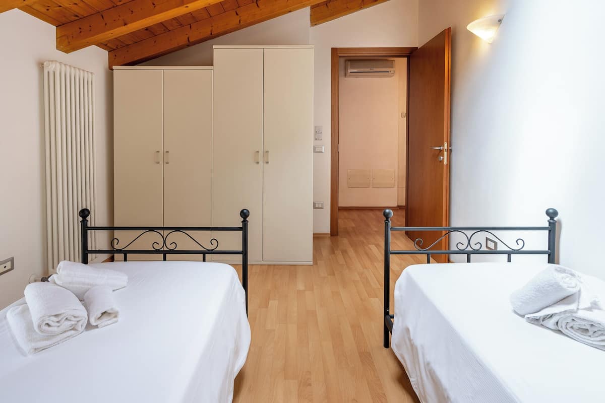 Een slaapkamer met twee bedden, houten vloeren en een plafond met zichtbare balken.