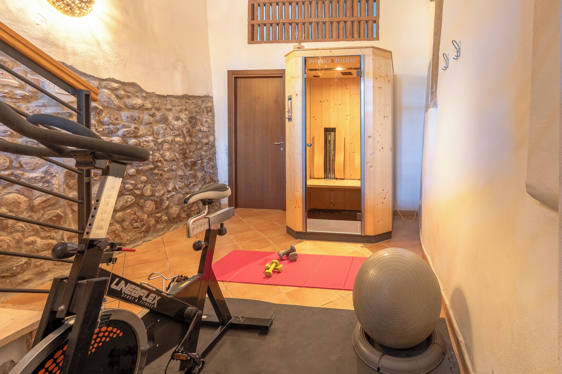 A home gym with a stationary bike, a massage chair, and a yoga mat.