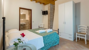 Une chambre à coucher avec un lit, un téléviseur fixé au mur, une armoire et une chaise.