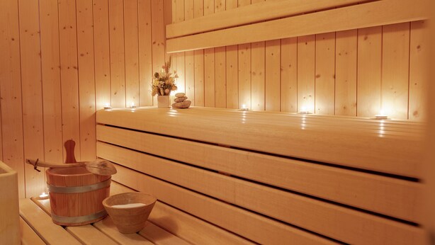 Un sauna en bois, avec des bancs, un seau et un récipient.