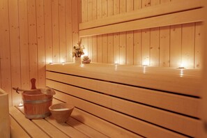 Een houten sauna met banken, een emmer en een kom.