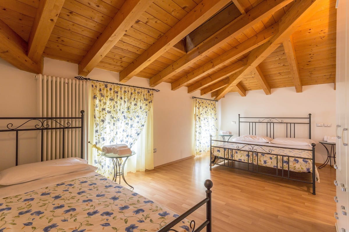 Een slaapkamer met twee bedden, houten vloeren en een schuin dak.