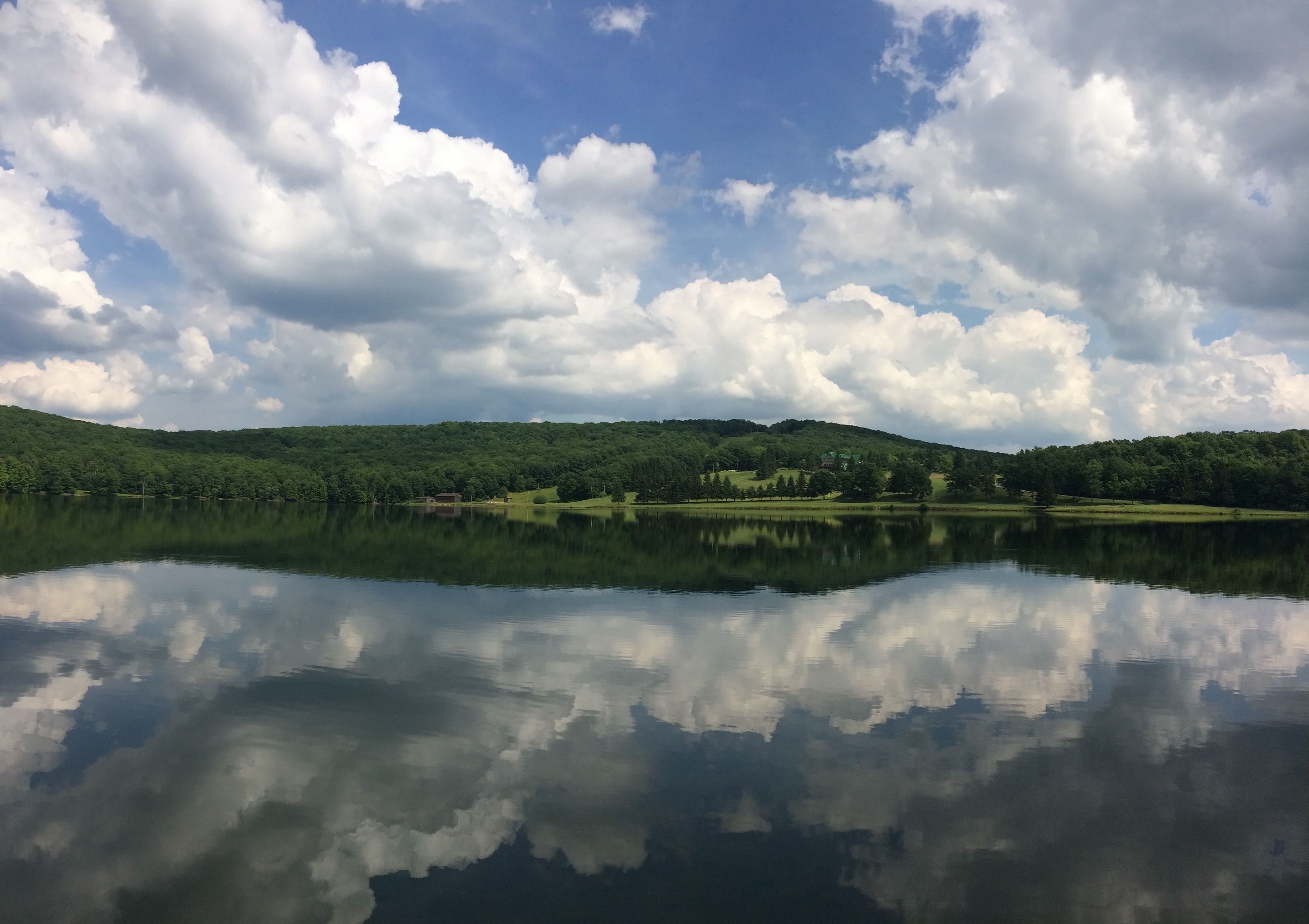 A calm lake with a reflection of the sky and clouds.