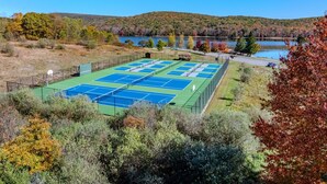 Un complesso di campi da tennis con più campi, circondato da alberi e un lago.